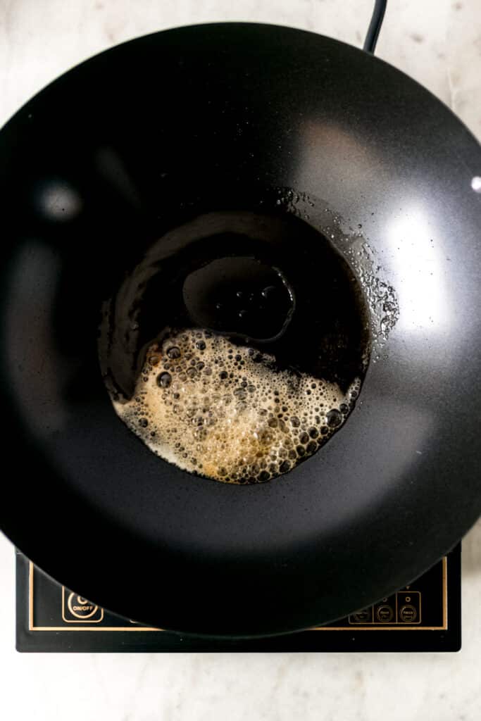 melted butter and cooking oil in a wok over a burner