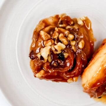 Close up view of two sticky buns on a white plate.