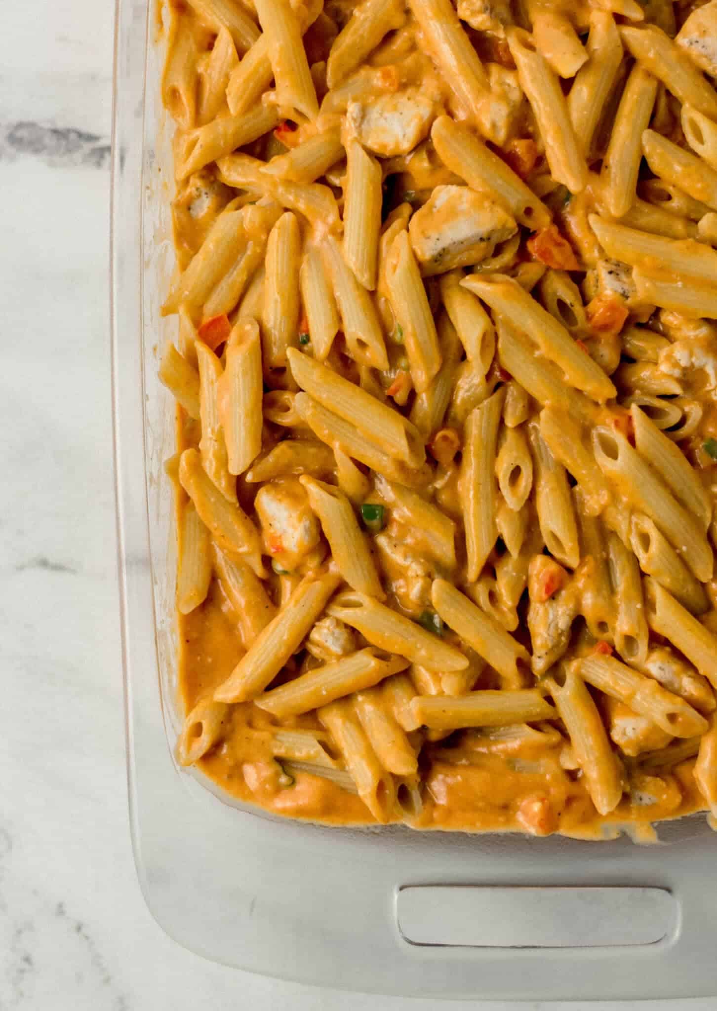 pasta and sauce added to glass baking dish 