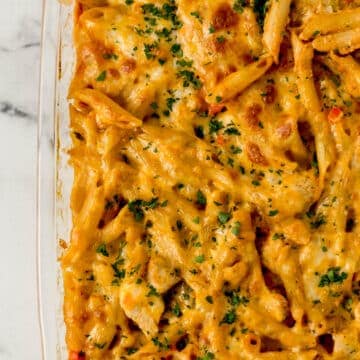 overhead view of finished enchilada pasta in glass baking dish topped with fresh chopped parsley