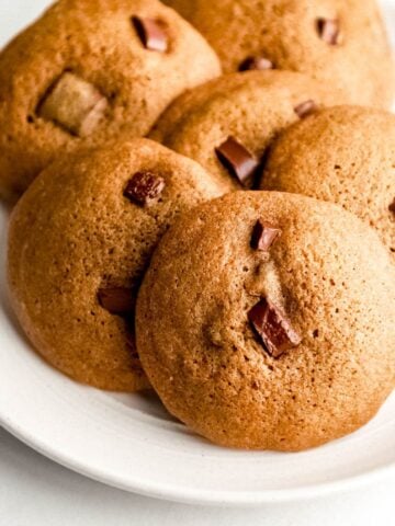 Close up front view of baked coffee cookies on white plate on white surface.