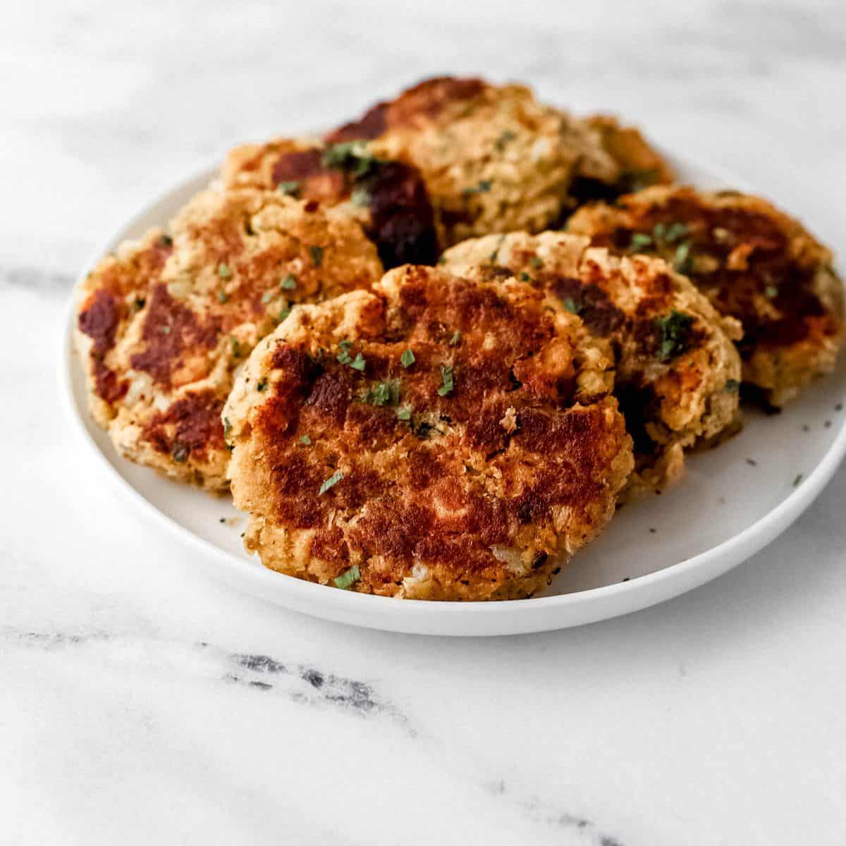 Finished salmon patties on white plate on marble surface.
