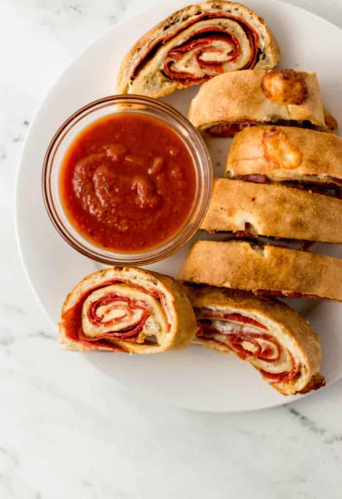 finished pepperoni bread recipe on large white plate with small glass bowl of dipping sauce