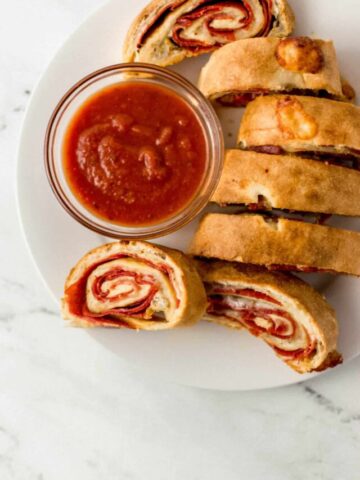 finished pepperoni bread recipe on large white plate with small glass bowl of dipping sauce