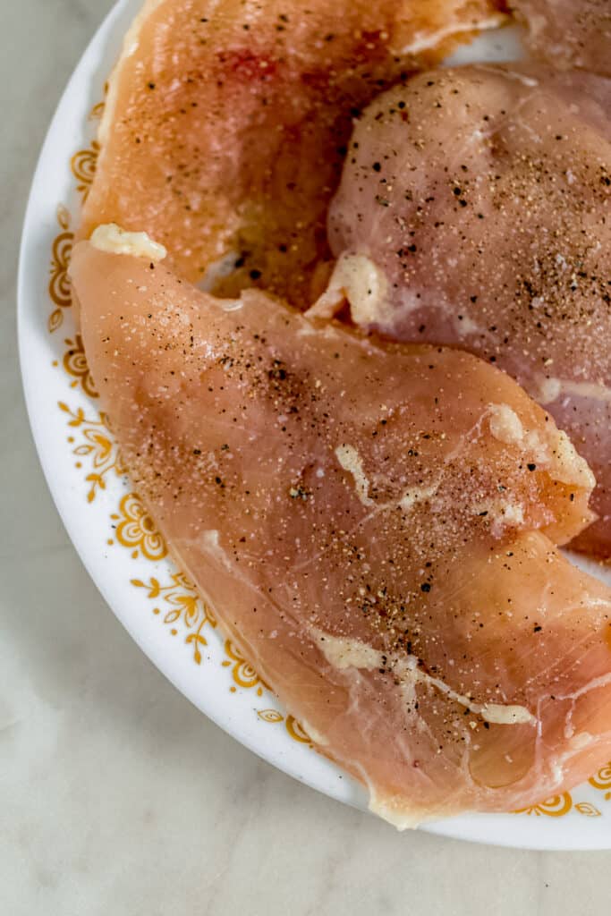 raw chicken on plate seasoned with salt and black pepper