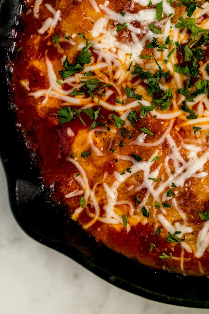close up side view chicken mozzarella bake in cast iron skillet 
