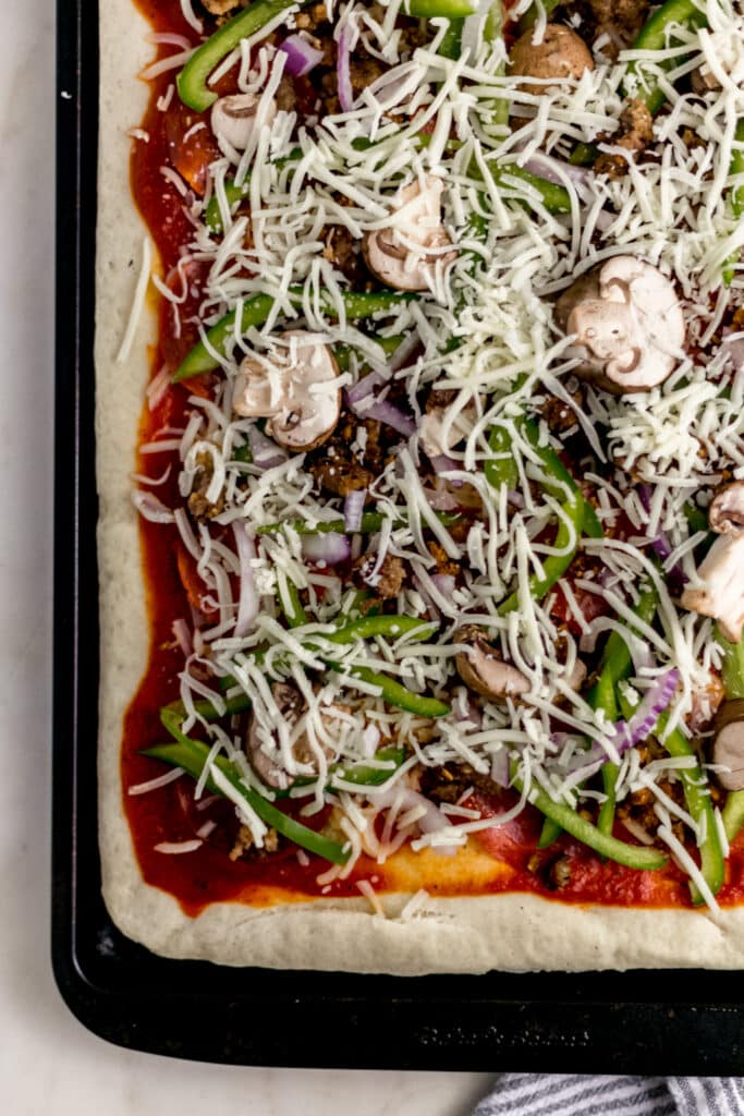 supreme pizza on baking sheet before baking