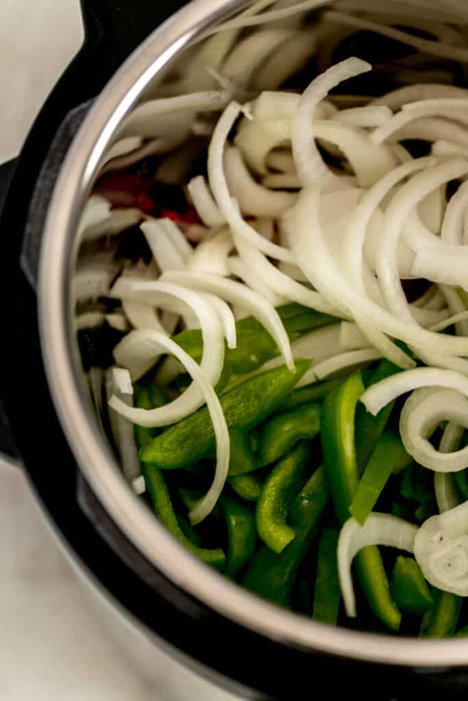 sliced onion and green bell pepper on top of steak in instant pot