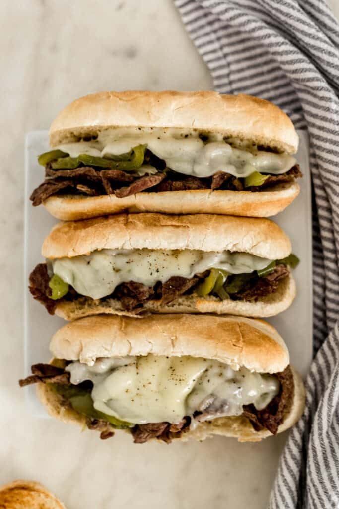 overhead view instant pot philly cheesesteaks on white square plate with napkin