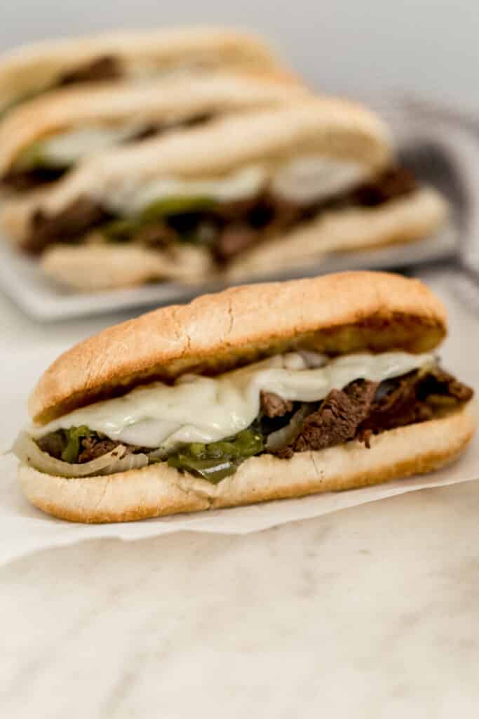 close up side view philly cheesesteak with more in background