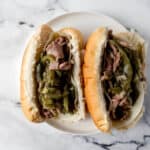 overhead view of two finished cheesesteaks on a white plate on a marble surface