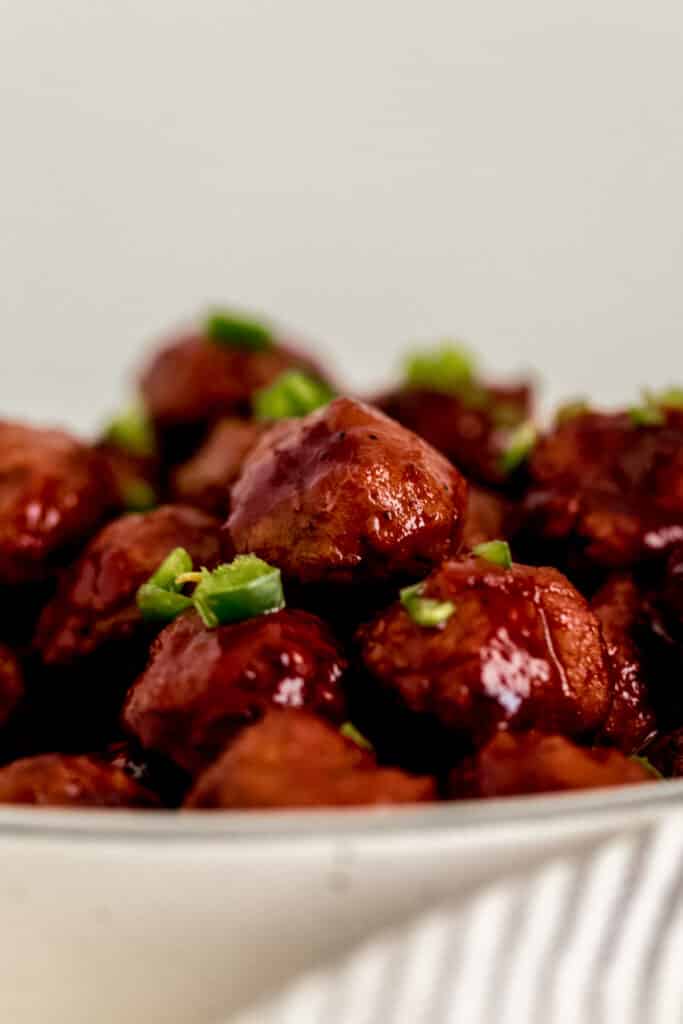 close up side view instant pot sweet and spicy meatball in white serving bowl 