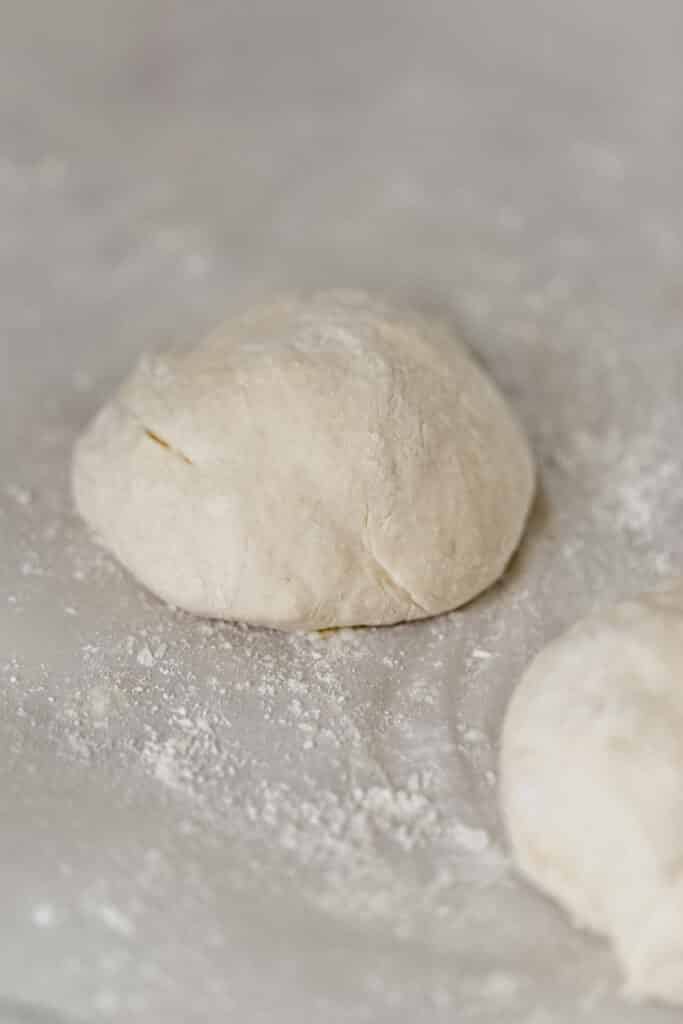 yeast free pizza dough in two balls on lightly floured parchment paper