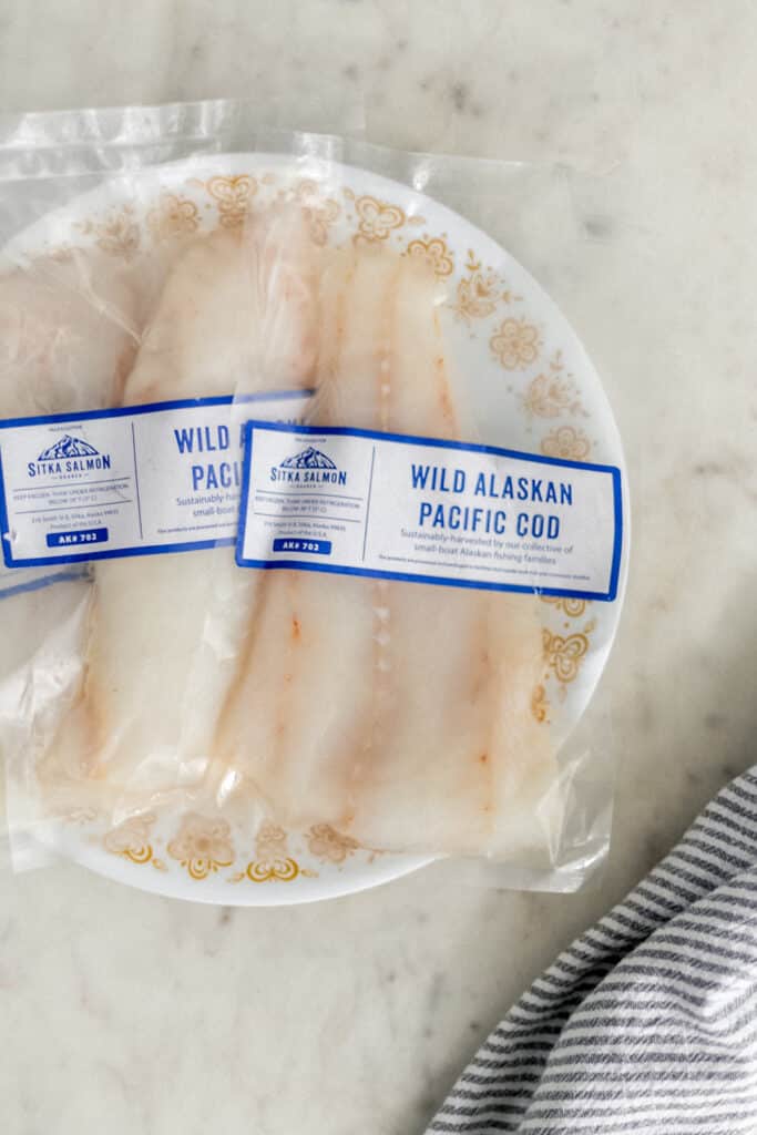 packets of fresh wild Alaskan Pacific cod in plastic on plate with napkin