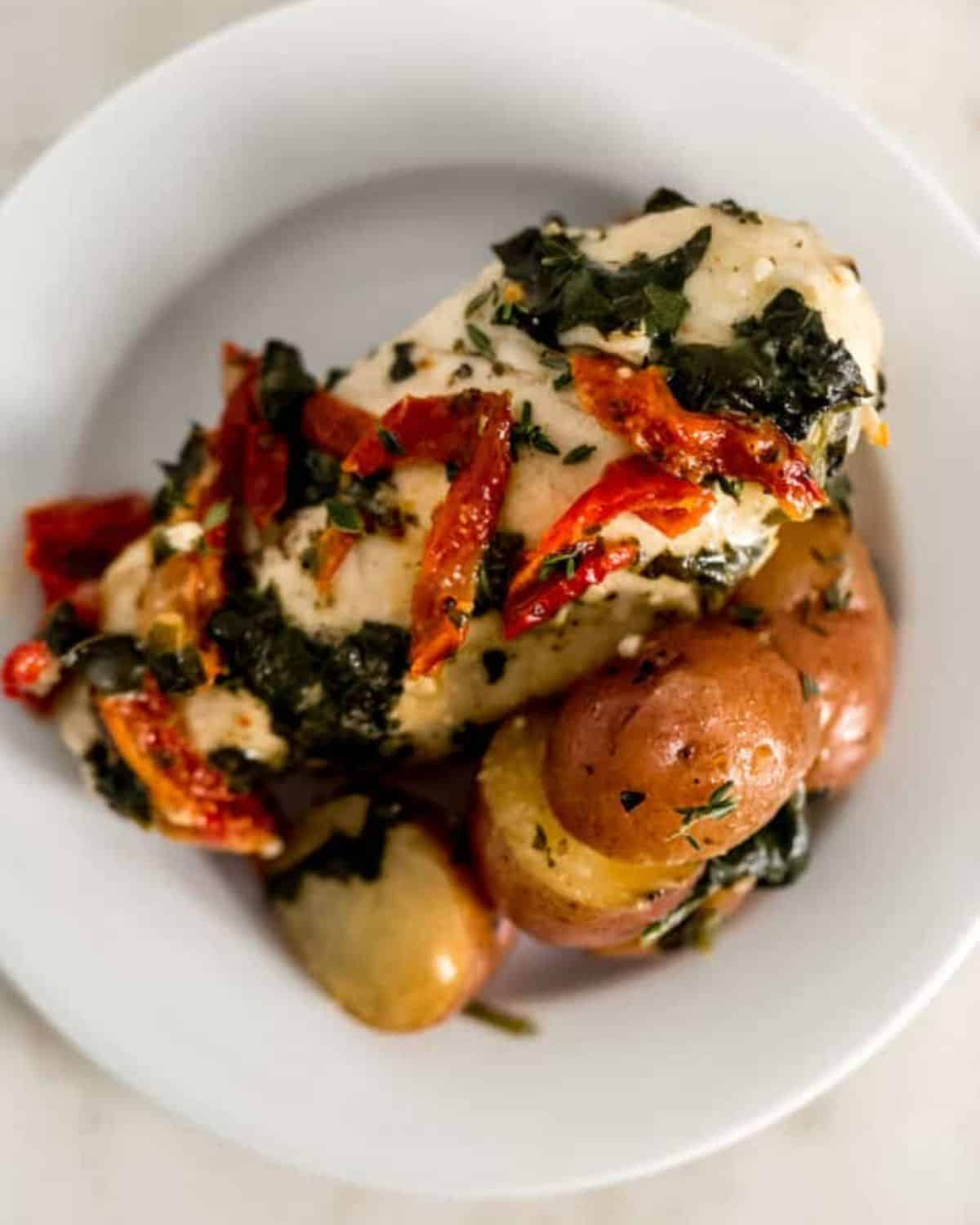 Overhead view of finished chicken and potatoes on a plate.