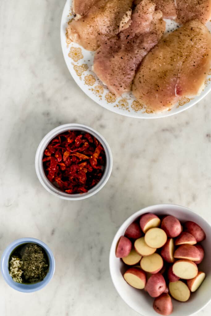 ingredients for sun dried tomato chicken and potatoes in bowls and plate