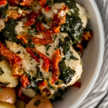 close up view of sun dried tomato chicken and potatoes in white serving bowl