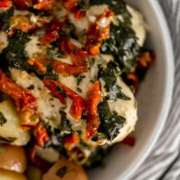 close up view of sun dried tomato chicken and potatoes in white serving bowl