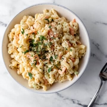 overhead bowl of pasta salad beside a fork on marble surface