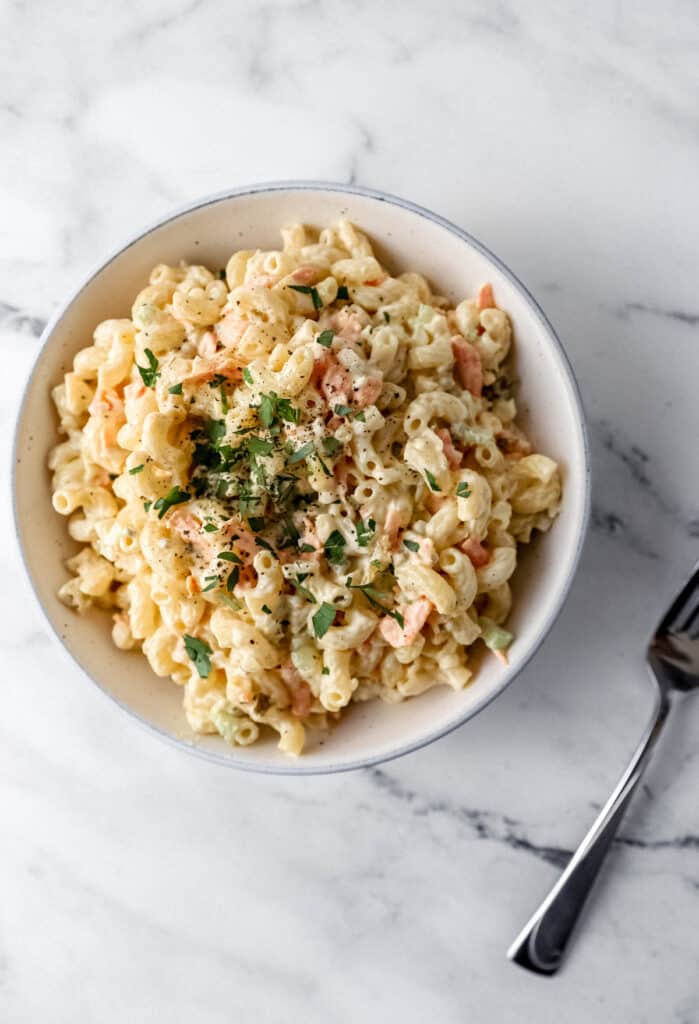 overhead bowl of pasta salad beside a fork on marble surface