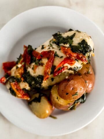 white plate with serving of sun dried tomato chicken and potatoes
