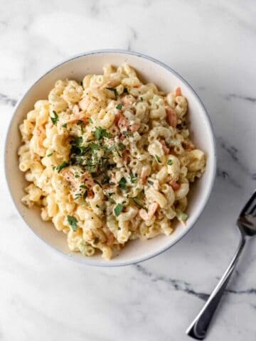 overhead bowl of pasta salad beside a fork on marble surface