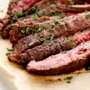 Close up view of sliced steak on parchment paper.