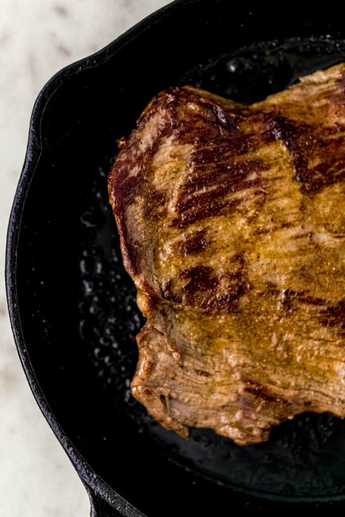 cooked flank steak in cast iron skillet