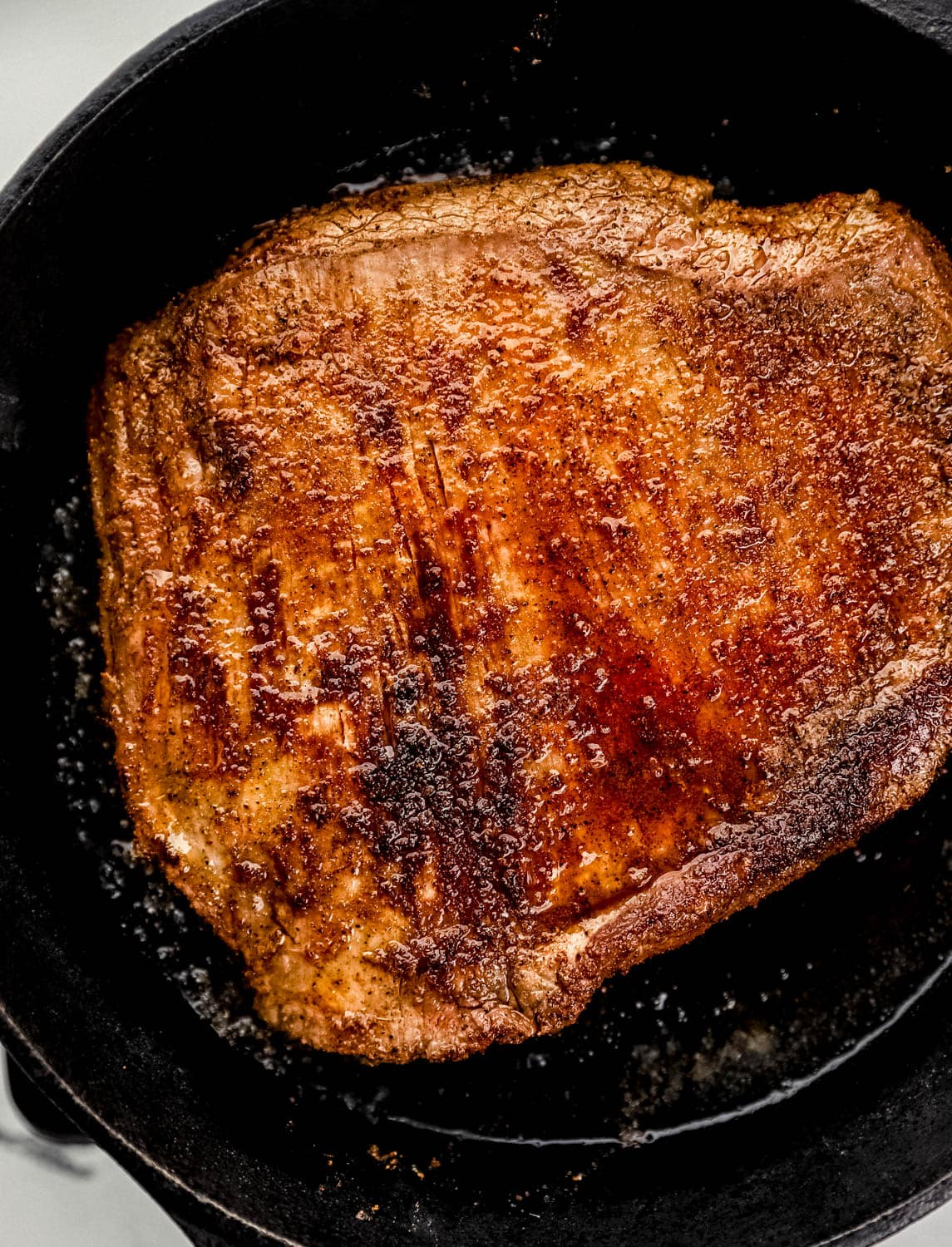 Overhead view of seared steak in cast iron skillet.
