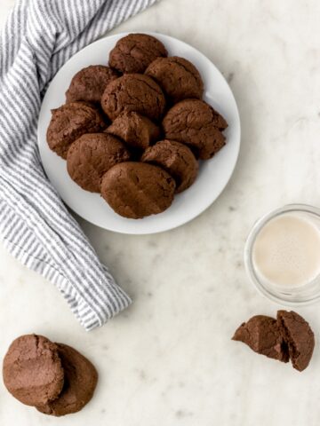 chocolate sugar cookies on a white plate with a glass of milk and cloth napkin