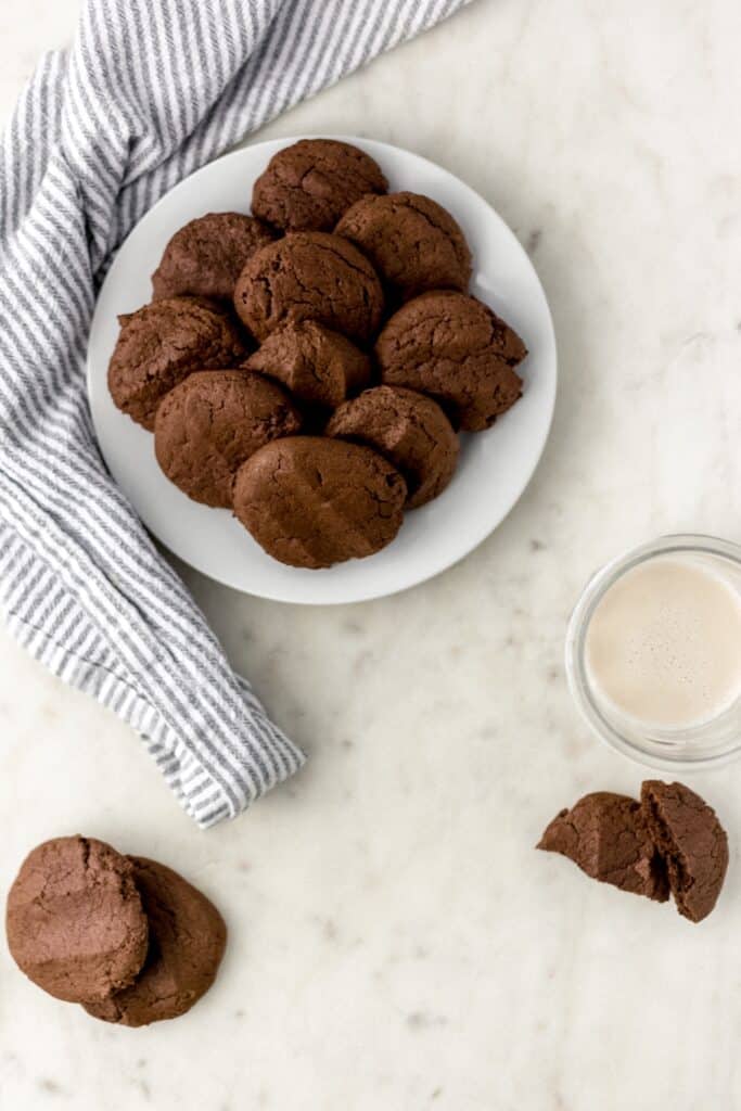 chocolate sugar cookies on a white plate with a glass of milk and cloth napkin 
