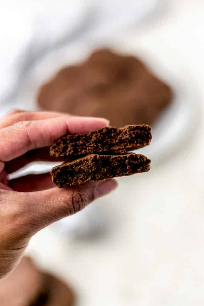 hand holding chocolate cookie cut in half 