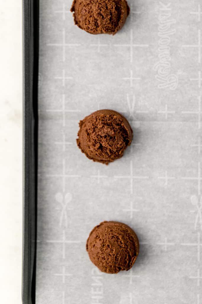 chocolate cookie dough scooped on parchment lined baking sheet before baking 