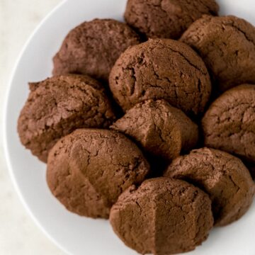 white plate with a batch of chocolate cookies on it.