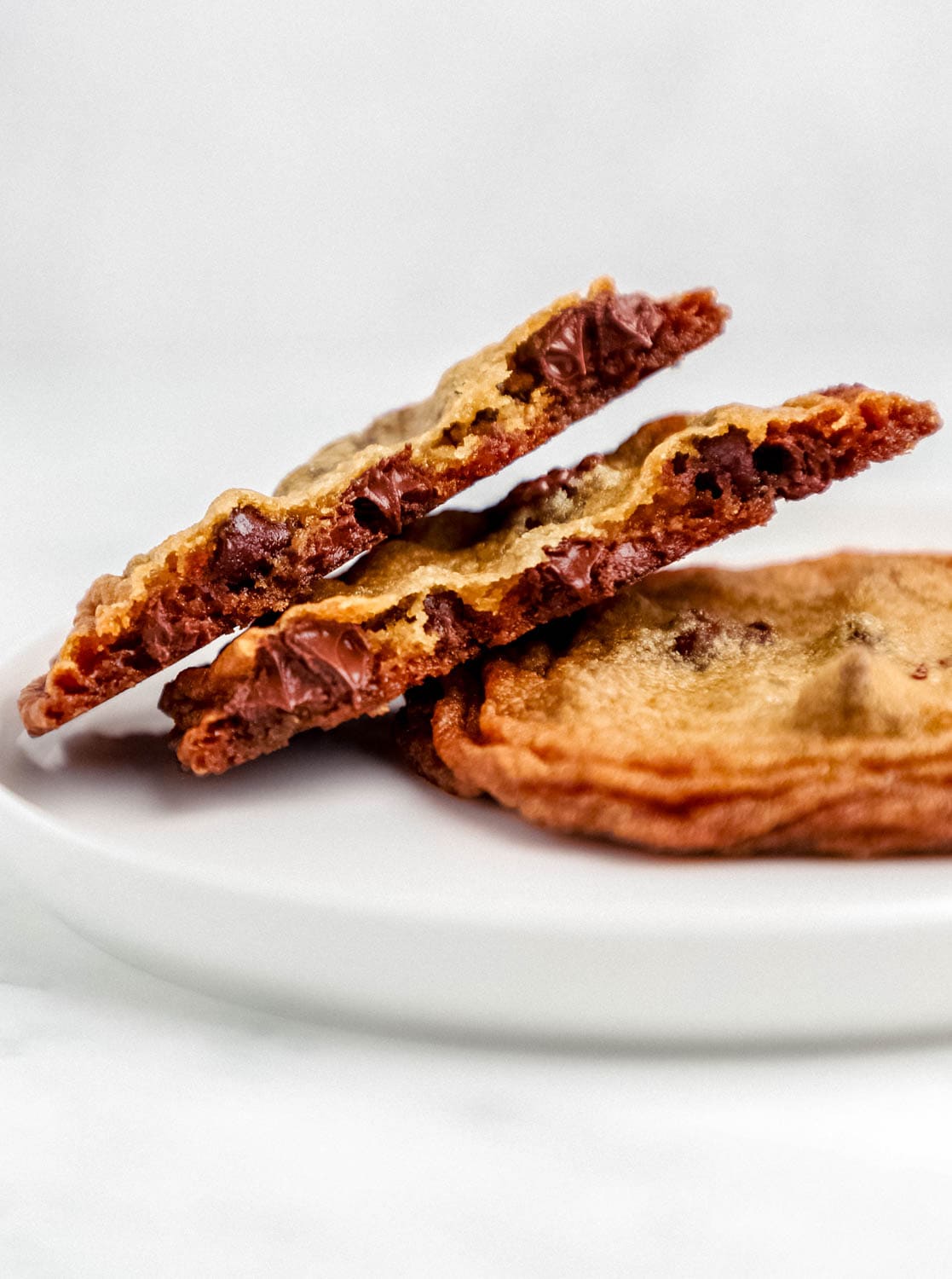 Close up view of two cookies on a plate with one broke in half. 