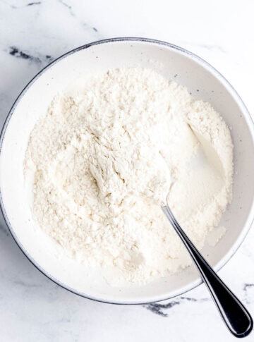 Overhead view of dry ingredients in white bowl with spoon.
