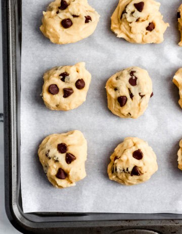 Cookie dough scooped on parchment lined baking sheet.