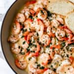 Overhead view of finished garlic butter shrimp in pan with bread.