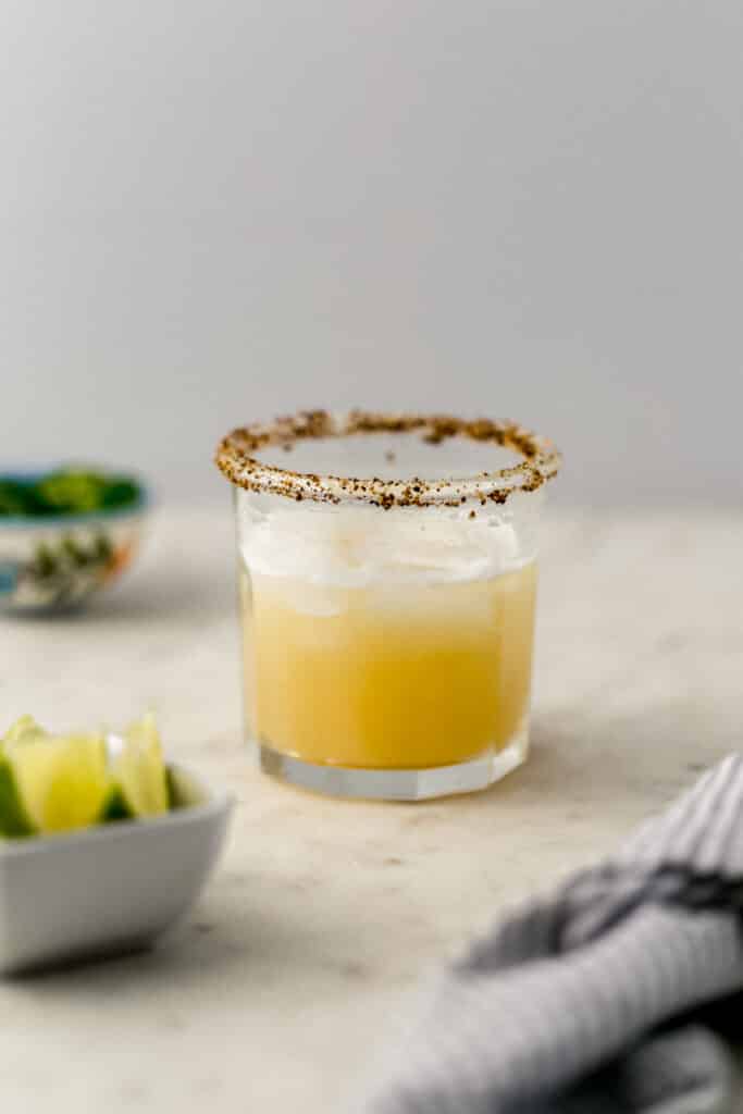 close up side view spicy margarita with lime wedges in a small white bowl