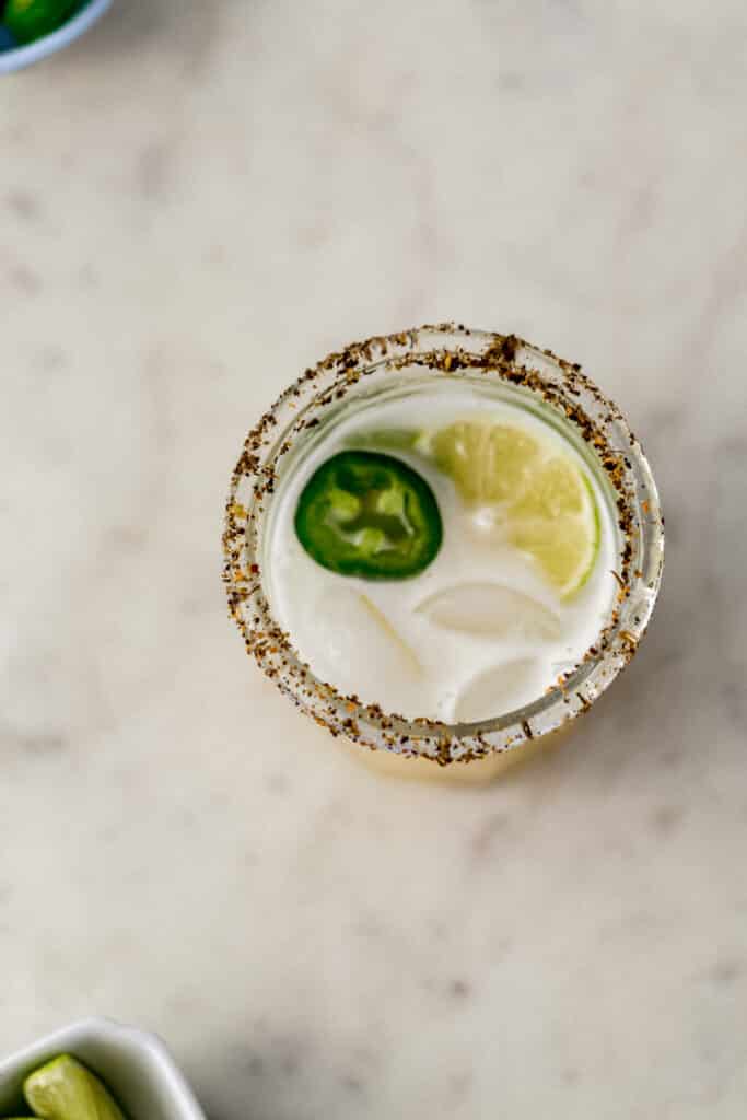 jalapeno margarita in a glass with jalapeno slices and lime