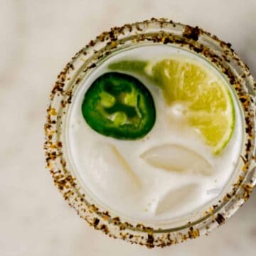 overhead view jalapeno margarita in a glass with jalapeno slices and lime