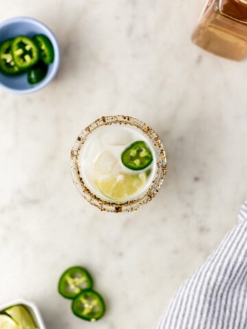 spicy margarita in a glass with jalapeno, lime, and cloth napkin