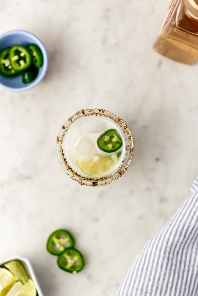 spicy margarita in a glass with jalapeno, lime, and cloth napkin