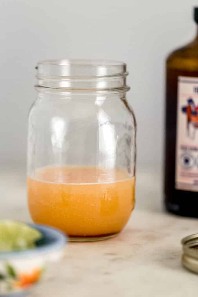 jar with ingredients for kombucha margarita in it next to bottle of kombucha