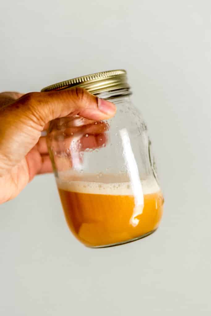 hand holding jar with lid on it with ingredient for margarita inside of it. 