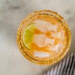 overhead view kombucha margarita with lime and ice in sugar rimmed glass.
