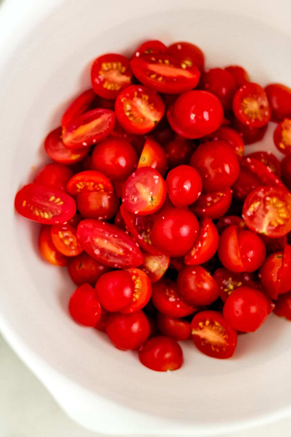 Cut tomato halved in a white mixing bowl.