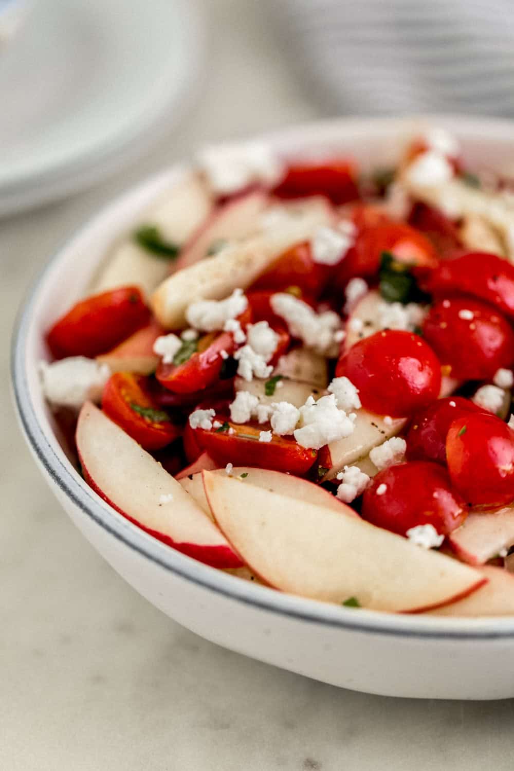 Close up front view of salad in a bowl topped with feta cheese.