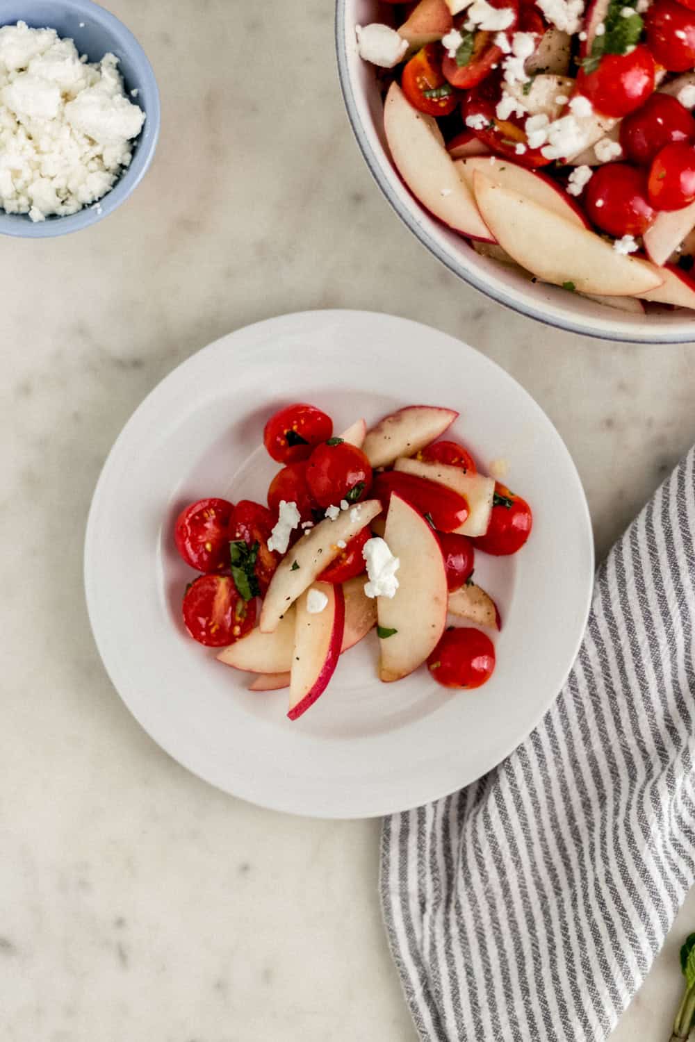 Serving of finished salad on a white plate with the rest in the background.