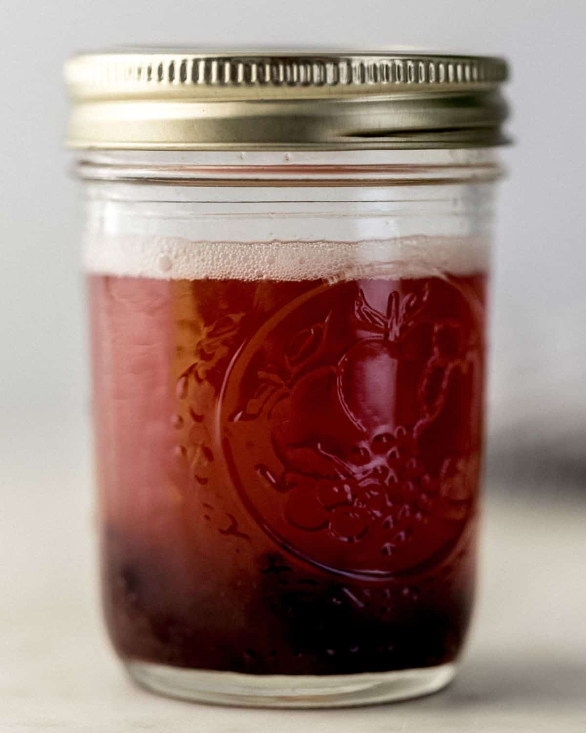 Close up side view of shaken margarita in jar with lid. 